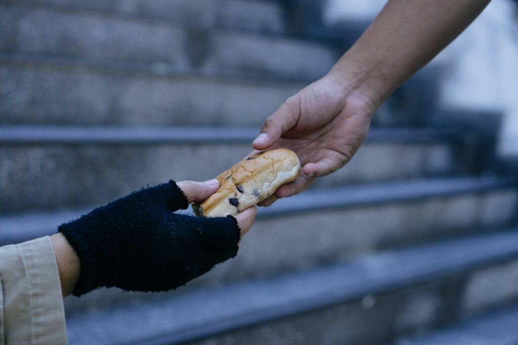 Man giving bread to hungry homeless beggar man sitting in city.Giving concept.